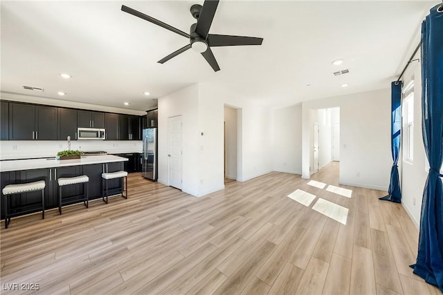 living room featuring light wood-style floors, recessed lighting, visible vents, and baseboards