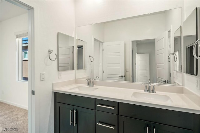 bathroom with double vanity, a sink, and baseboards