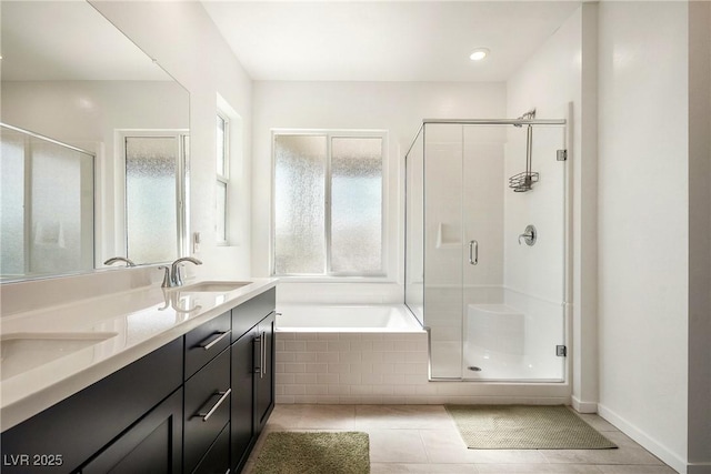 bathroom featuring a bath, a stall shower, double vanity, and a sink