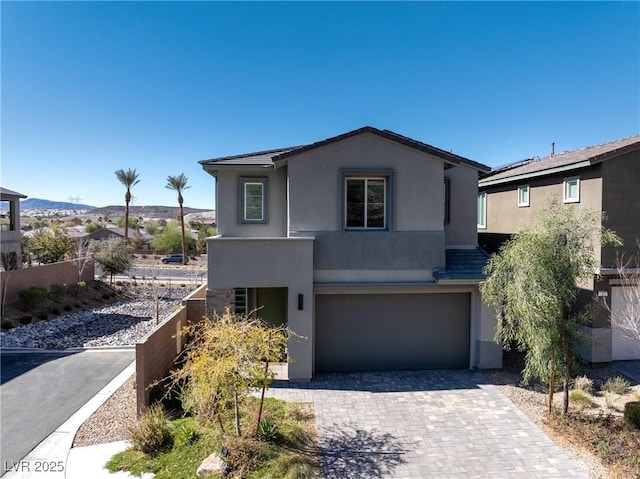 view of front of home featuring a garage, a mountain view, decorative driveway, and stucco siding