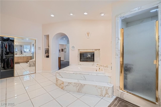 bathroom featuring tile patterned flooring, a garden tub, vanity, and a shower stall