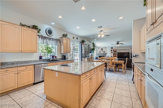 kitchen with light brown cabinetry, white appliances, a kitchen island, and visible vents