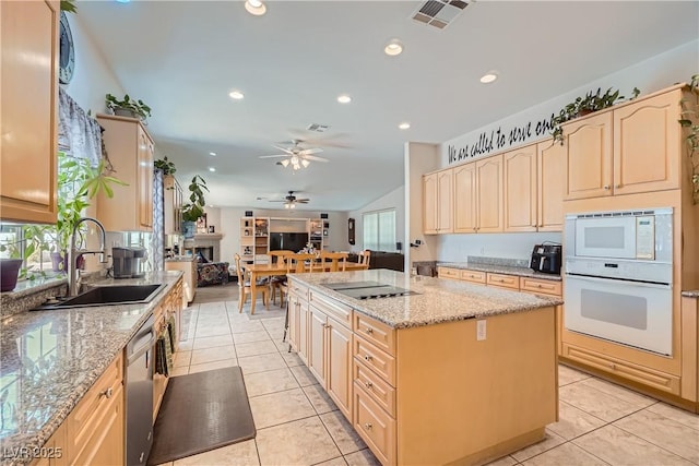 kitchen featuring light tile patterned floors, white appliances, a sink, and light stone counters