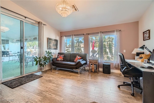 office featuring vaulted ceiling, wood finished floors, visible vents, and a healthy amount of sunlight