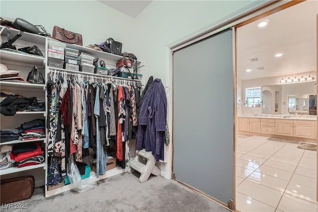 spacious closet featuring light tile patterned flooring, visible vents, and light colored carpet