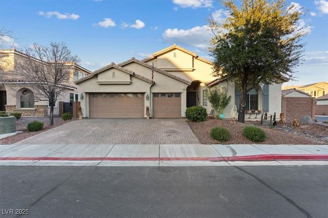 mediterranean / spanish home with a garage, fence, decorative driveway, and stucco siding