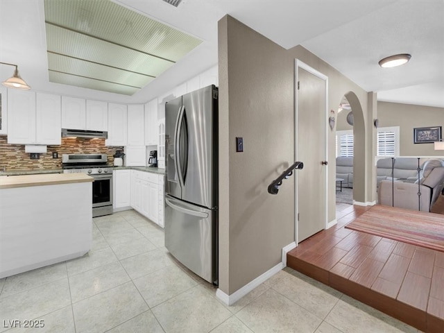 kitchen featuring light tile patterned floors, arched walkways, appliances with stainless steel finishes, white cabinetry, and exhaust hood