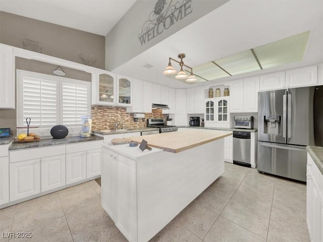 kitchen featuring stainless steel appliances, white cabinets, glass insert cabinets, and light tile patterned floors