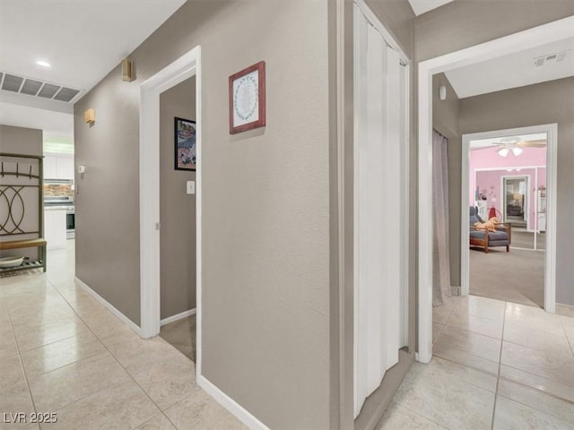 corridor with light tile patterned floors, visible vents, and baseboards