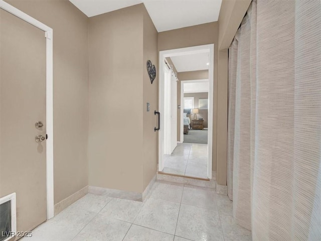 hall with baseboards and light tile patterned floors