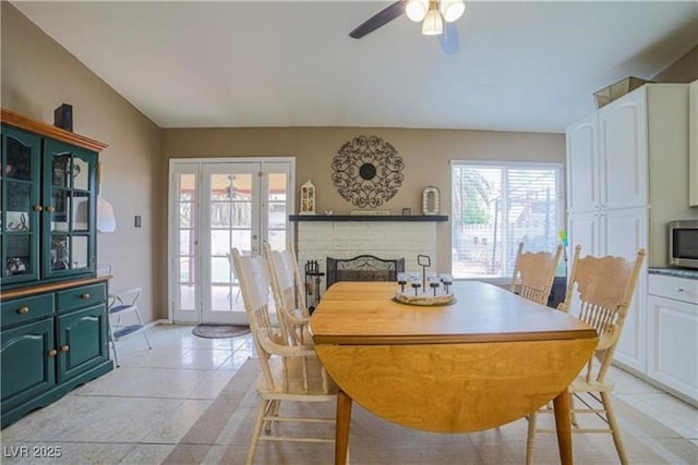 dining space featuring light tile patterned floors, ceiling fan, and a fireplace