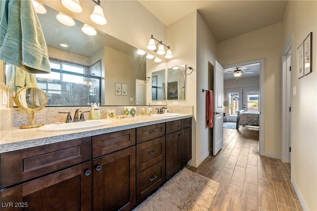 ensuite bathroom featuring double vanity, wood finish floors, a sink, and a shower stall