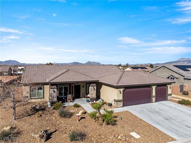 view of front of house with a garage, concrete driveway, a tile roof, and a mountain view