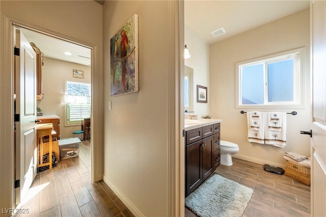 bathroom featuring wood finish floors, visible vents, toilet, vanity, and baseboards