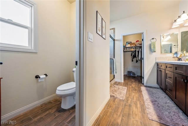 full bathroom with wood tiled floor, a walk in closet, vanity, and toilet