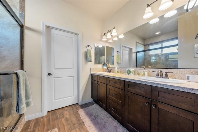 full bathroom featuring double vanity, wood finished floors, a sink, and a shower stall