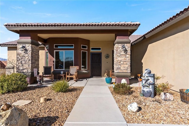 view of exterior entry featuring stone siding, a porch, and stucco siding