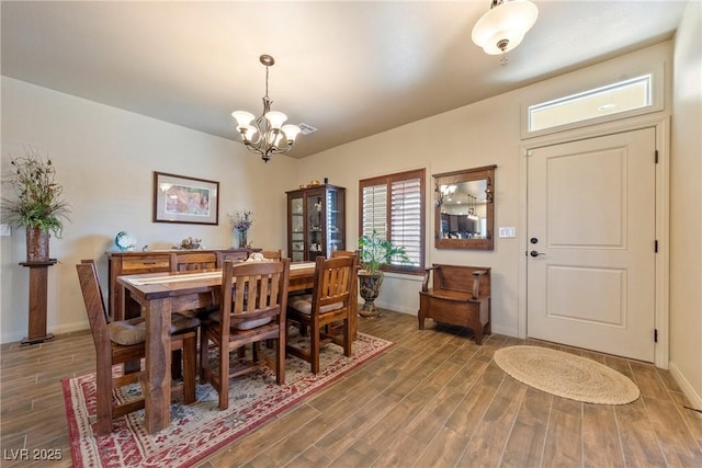 dining area featuring baseboards, an inviting chandelier, and wood finished floors