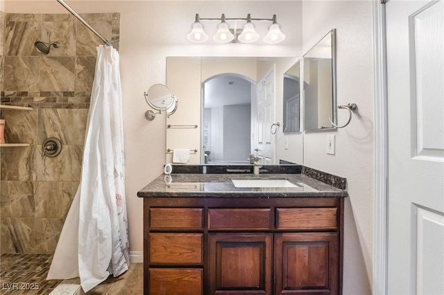 bathroom with tiled shower and vanity