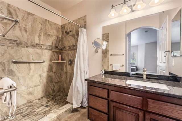 bathroom with tiled shower and vanity