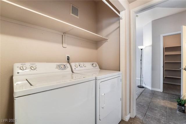 washroom with washer and clothes dryer, visible vents, dark tile patterned flooring, laundry area, and baseboards