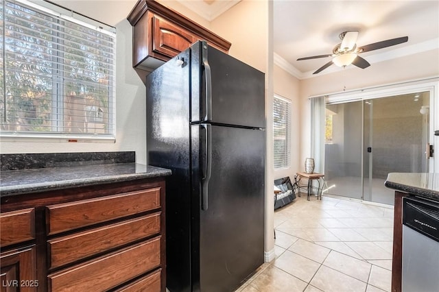 kitchen featuring light tile patterned floors, a ceiling fan, stainless steel dishwasher, freestanding refrigerator, and crown molding