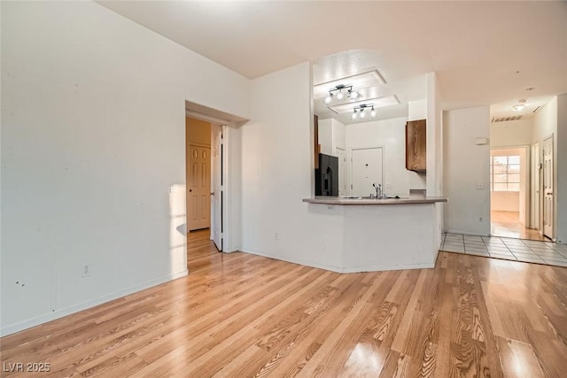 unfurnished living room featuring light wood-style flooring and a sink