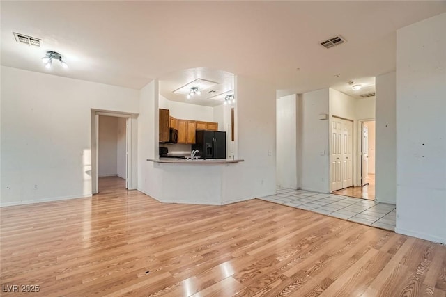 unfurnished living room with light wood-style flooring, a sink, and visible vents