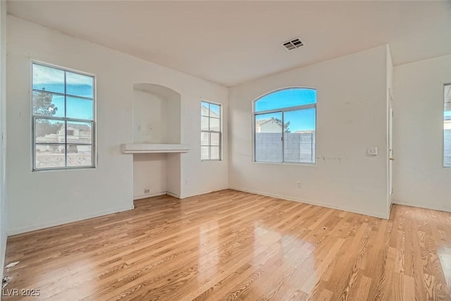 unfurnished room featuring baseboards, visible vents, and light wood finished floors