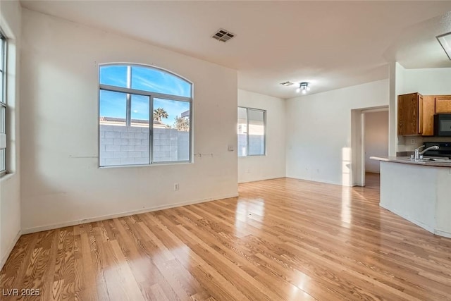 unfurnished living room featuring light wood-style flooring, visible vents, and baseboards