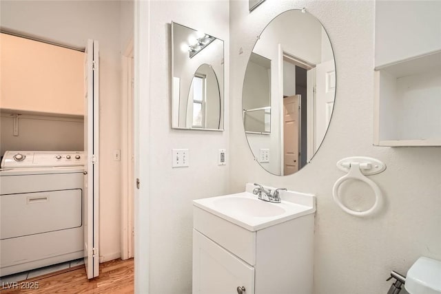 bathroom with toilet, washer / dryer, wood finished floors, and vanity