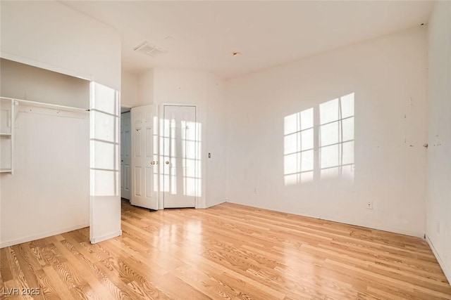 unfurnished bedroom featuring light wood finished floors, two closets, and visible vents