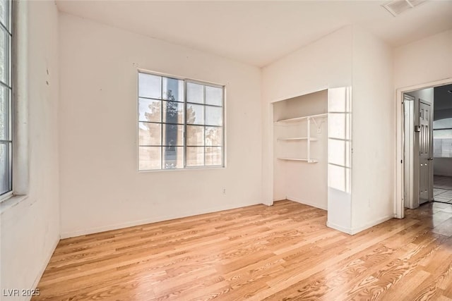 unfurnished bedroom featuring a closet, wood finished floors, and visible vents