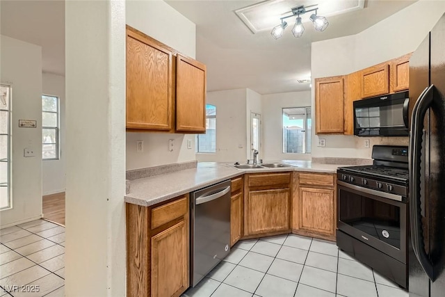 kitchen with light tile patterned floors, black appliances, a sink, and light countertops