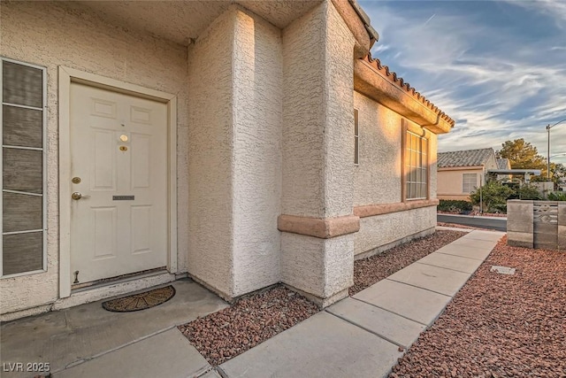 property entrance with a tiled roof and stucco siding