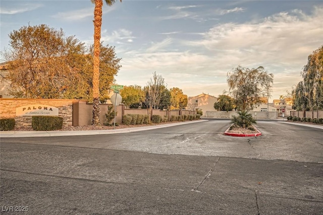 view of street with curbs, a gated entry, and traffic signs