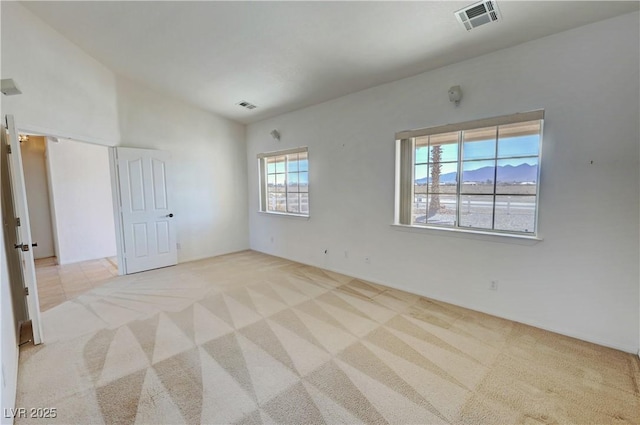 carpeted empty room with lofted ceiling and visible vents