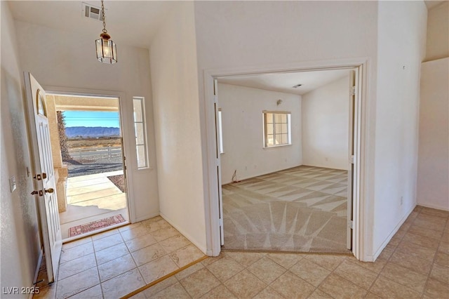 entryway with light colored carpet, visible vents, and a high ceiling