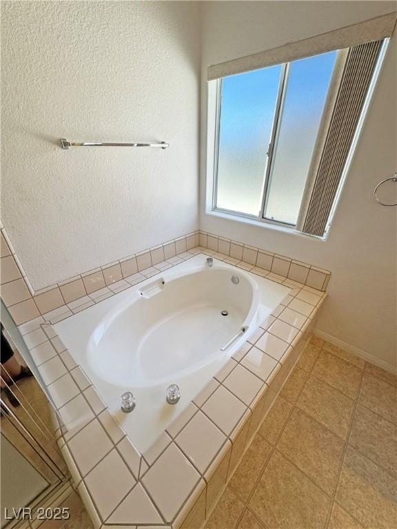 full bath featuring a garden tub and baseboards