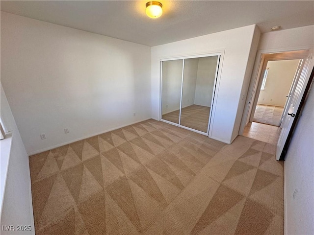 unfurnished bedroom featuring light carpet and a closet