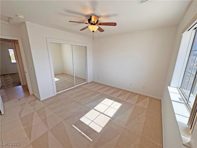 unfurnished bedroom with a closet, light carpet, and ceiling fan