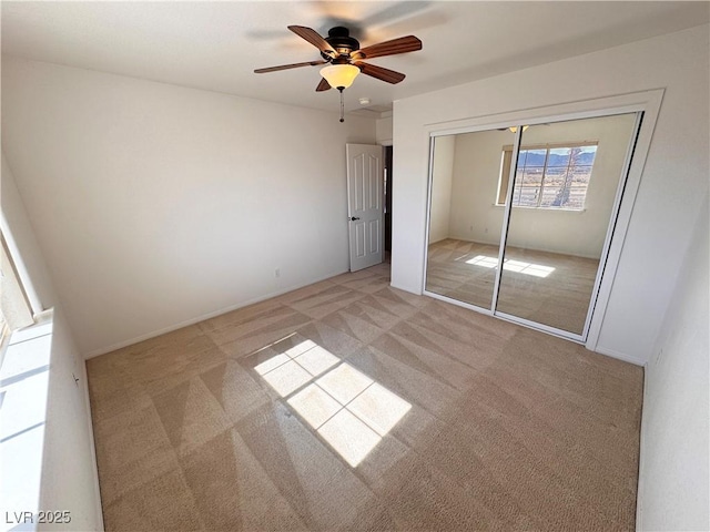 unfurnished bedroom featuring light carpet, a closet, and a ceiling fan