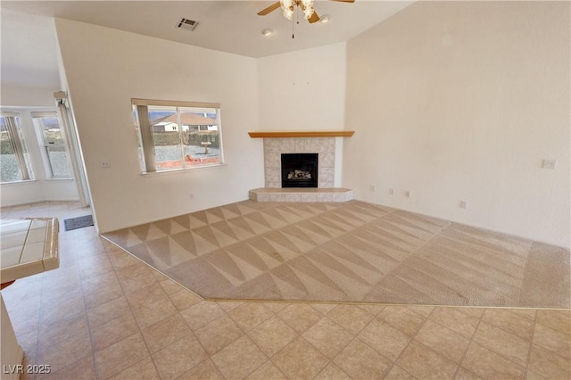 unfurnished living room featuring a tiled fireplace, tile patterned flooring, visible vents, and a ceiling fan