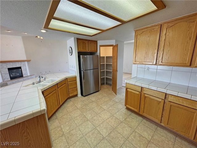 kitchen with open floor plan, freestanding refrigerator, a peninsula, light floors, and a sink