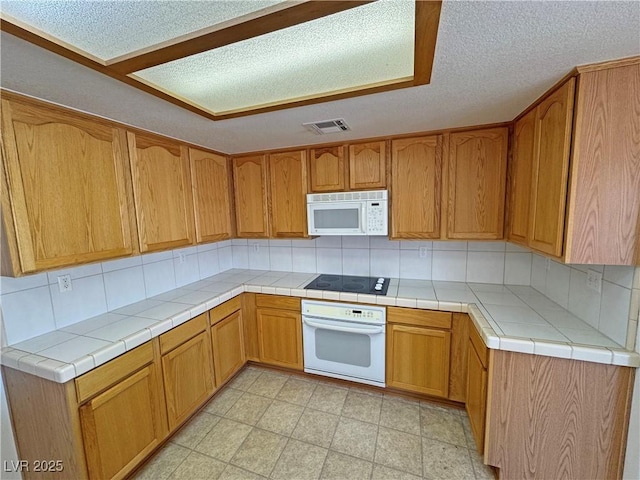 kitchen with brown cabinets, light floors, visible vents, backsplash, and white appliances