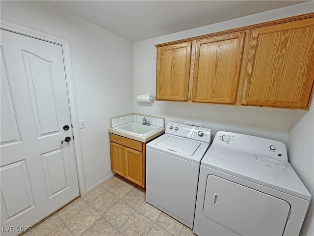 washroom with washing machine and dryer, a sink, baseboards, cabinet space, and light floors