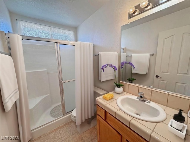 full bath featuring toilet, a textured ceiling, a shower stall, vanity, and tile patterned floors