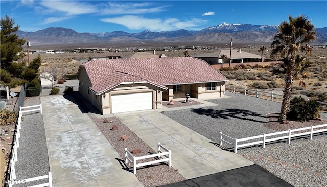 single story home featuring concrete driveway, a tile roof, fence, and a mountain view