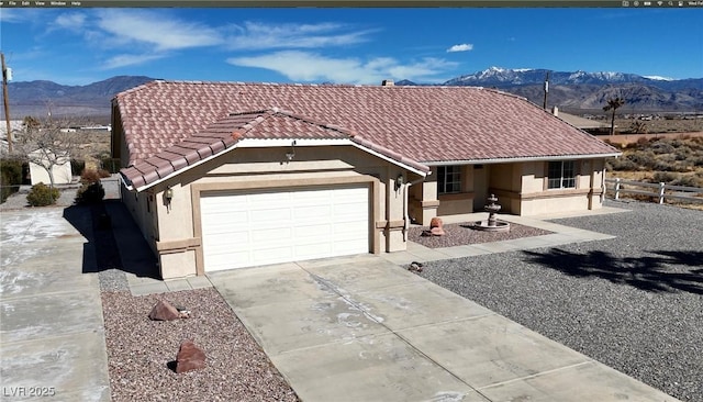 single story home featuring a garage, concrete driveway, a tiled roof, a mountain view, and stucco siding