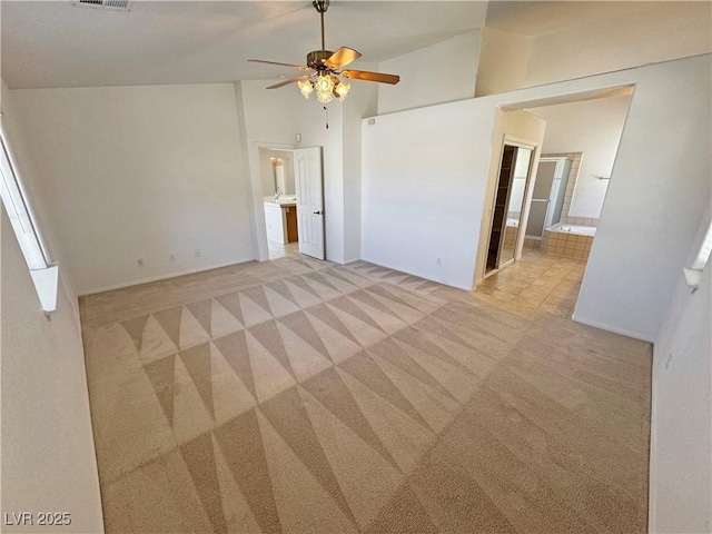 unfurnished bedroom with visible vents, a ceiling fan, light colored carpet, lofted ceiling, and ensuite bath